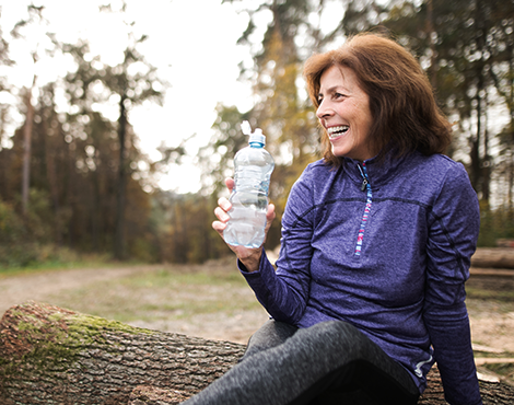 Woman taking a break from a hike, drinking from a bottle of water